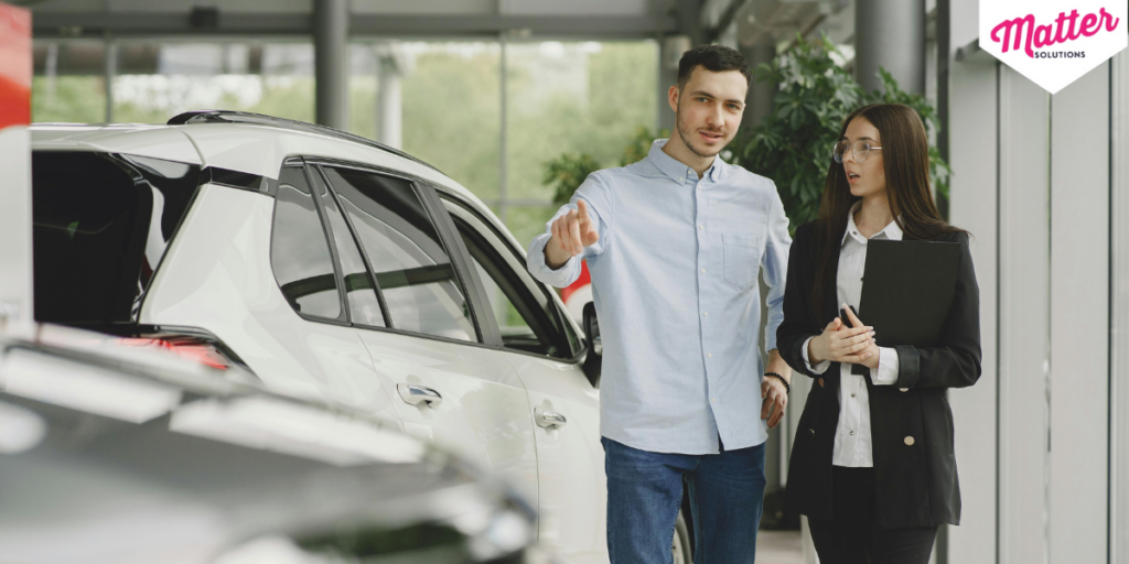 Customer and salesperson discussing a car in a showroom.